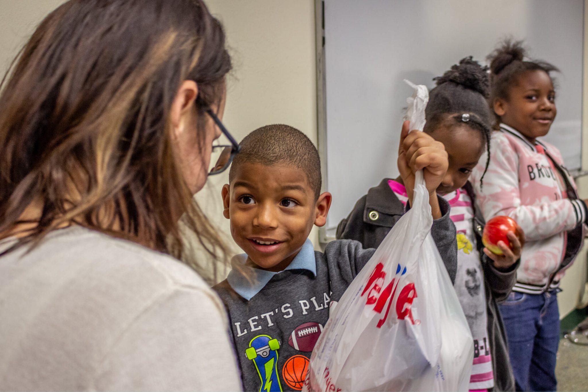 Homepage Photo of boy raising his bag of food