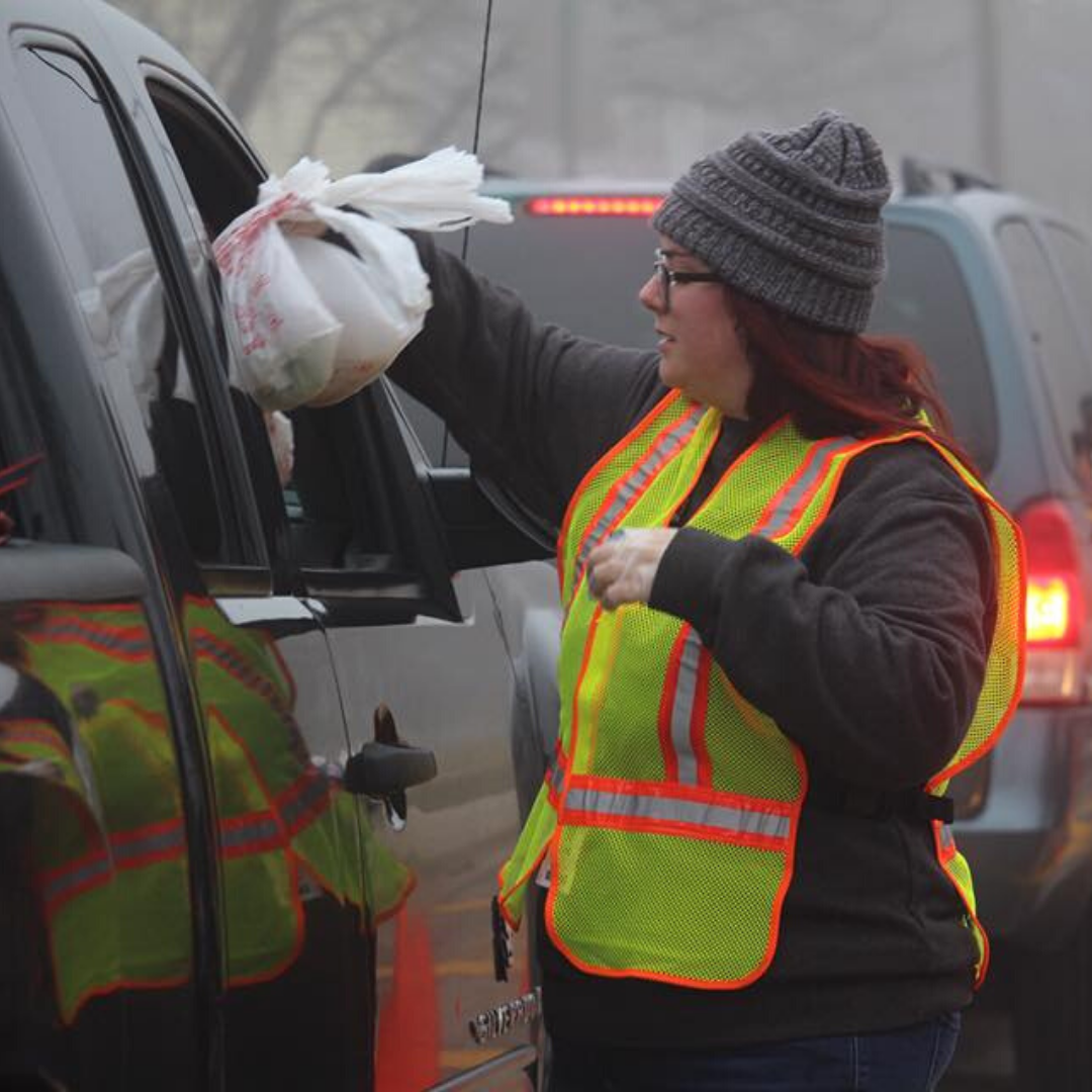 Photo of volunteer handing a bag of food to a recipient